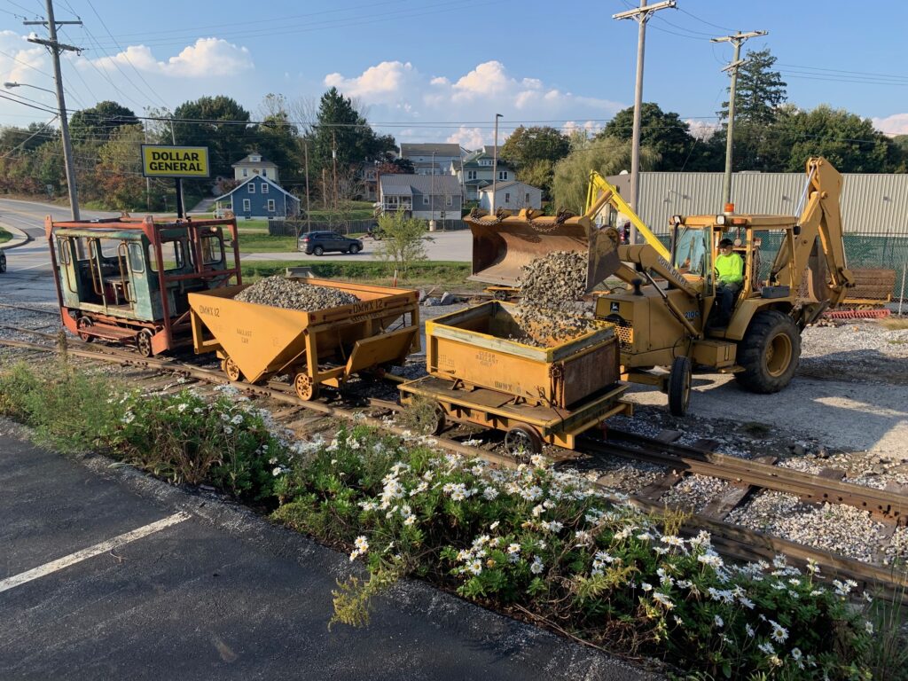 Loading ballast into work cars with the backhoe